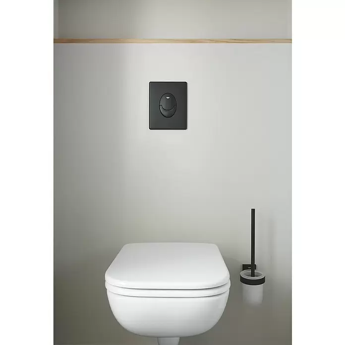 Grohe Start Betätigungsplatte - Schwarz, 2-Mengen-Spülung - Weißes Wand-WC mit schwarzer Spülplatte und passendem Toilettenbürstenhalter in einem modernen Badezimmer.