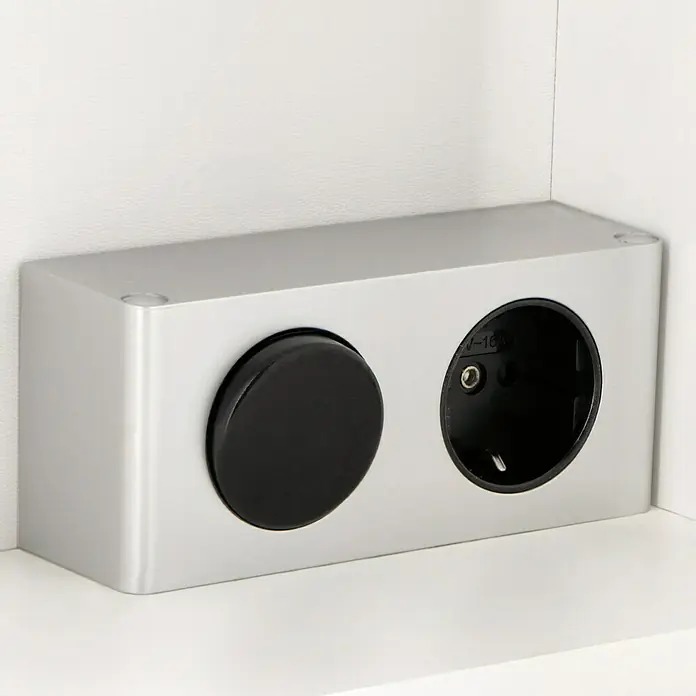 Riva LED-Spiegelschrank FloraB x H: 60 x 60 cm, Holz, Weiß - Eine silberne Steckdosenleiste mit einem schwarzen Knopf an einer weißen Wand.