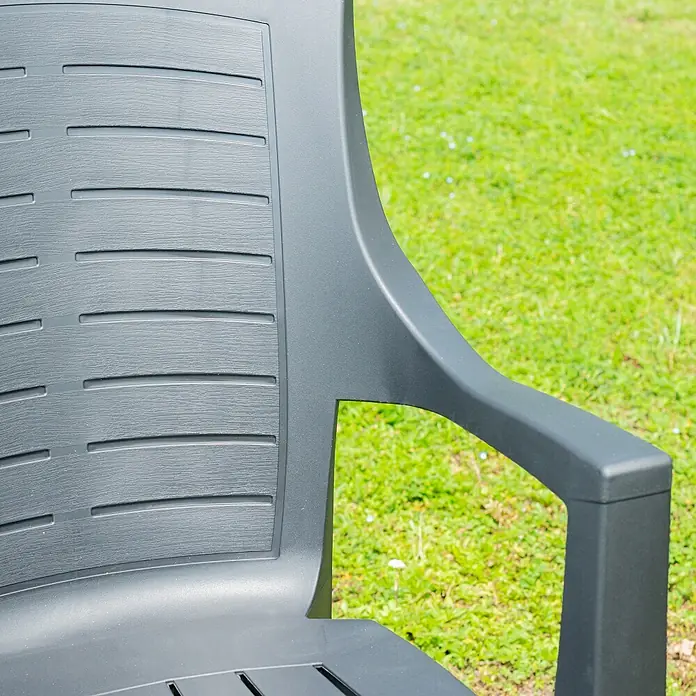 Progarden Stapelstuhl Talia - Stapelbar, Anthrazit, B x T x H: 60 x 55 x 91 cm - Nahaufnahme eines grauen Gartenstuhls aus Kunststoff mit Armlehne, der auf einer grünen Rasenfläche steht. Das Design ist modern und schlicht.