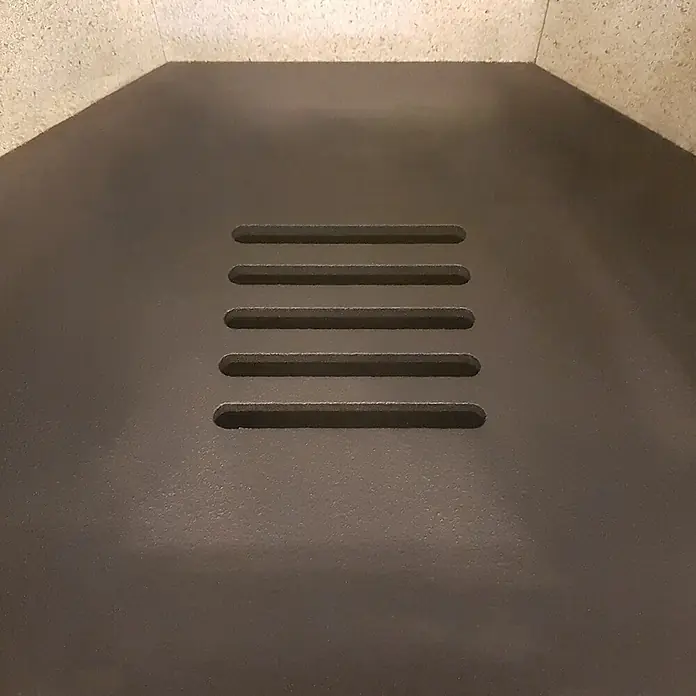 Justus Usedom 5 Kaminofen Usedom W+ 2.0 - 5,5 kW, Raumheizvermögen: 88 m³, Material Verkleidung: Speckstein, Schwarz/Speckstein - Nahaufnahme einer dunklen Ofenplatte mit fünf horizontalen Lüftungsschlitzen in der Mitte, die für eine gute Luftzirkulation sorgt.