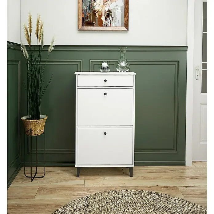 Meka Block Zapatero K-307 - L x An x Al: 25 x 61 x 110 cm, Blanco Soft, Número de compartimentos: 2 ud. - Un zapatero blanco con cajones y dos compartimentos se asienta en un piso de madera. Artículos decorativos como jarrón y vela encima del mueble.