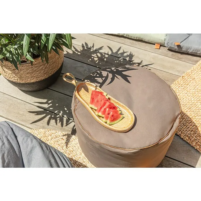 Sitting Point Sitzhocker Dotcom Jamie - Ø x H: 50 x 30 cm, Braun, 100 % Polyester - Holztablett mit saftiger Wassermelone auf einem grauen Pouf, daneben eine Topfpflanze und weitere Sitzgelegenheiten.