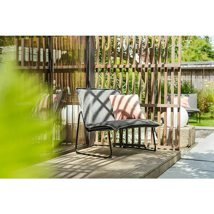 Sunfun Sarah Garten-Loungesessel - Anthrazit, B x T x H: 87 x 68 x 76 cm - Moderner grauer Outdoor-Sessel mit Kissen auf einer Holzterrasse, umgeben von einem stilvollen Holzgitter.