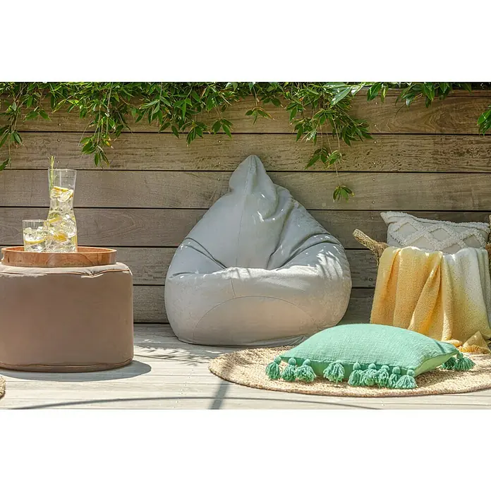 Juteteppich Nature 502 - Naturbraun, Durchmesser: 100 cm, 100 % Jute - Eine gemütliche Szene im Freien mit einem grauen Sitzsack, einem braunen Hocker mit Getränken und einem Korb mit Decken, ideal zum Entspannen.