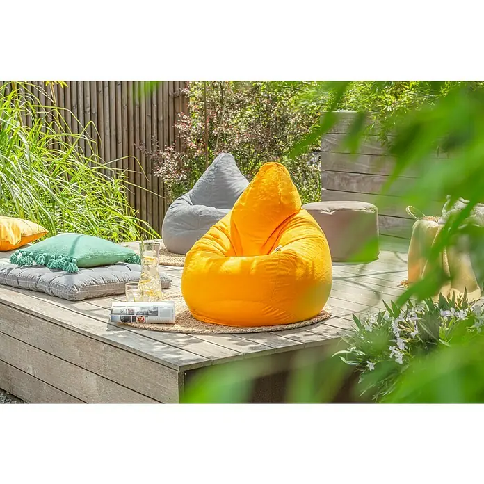 Juteteppich Nature 502 - Naturbraun, Durchmesser: 100 cm, 100 % Jute - Ein sonnengelber Sitzsack mit Kapuze und ein grauer Sitzsack auf einer Holzterrasse mit Kissen und Getränken.
