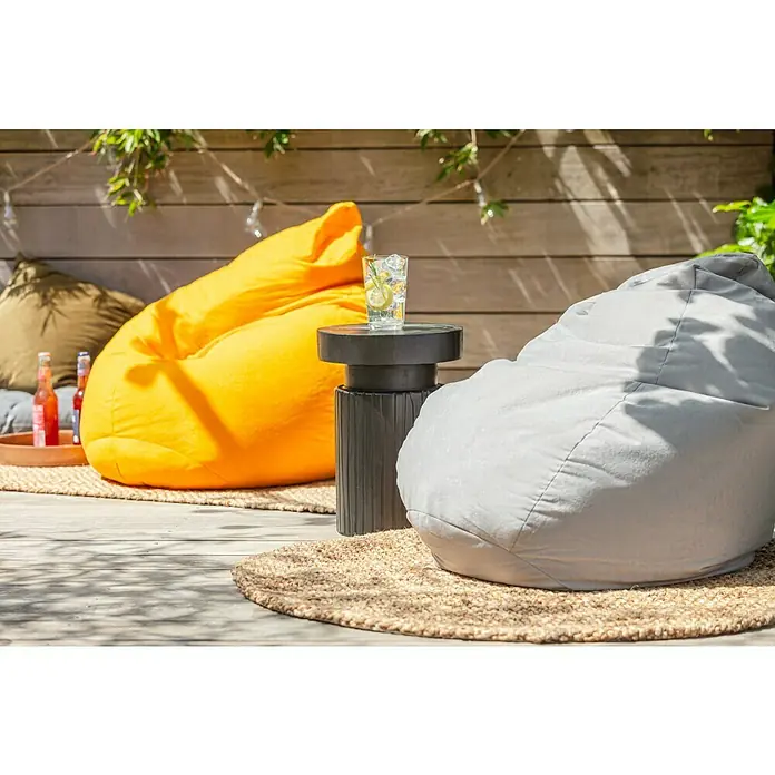 Sitting Point Sitzsack Beanbag Easy - L, Grau, 100 % Polyester - Entspannte Gartenszene mit farbenfrohen Sitzsäcken und einem stilvollen Beistelltisch mit Getränk auf einer sonnigen Terrasse.