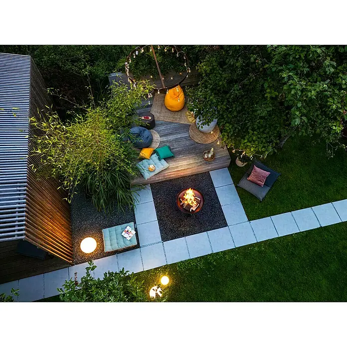 Juteteppich Nature 501 - Naturbraun, 230 x 160 cm, 100 % Jute - Luftaufnahme eines gemütlichen Gartens mit Feuerstelle, Sitzgelegenheiten und Beleuchtung für entspannte Abende im Freien.