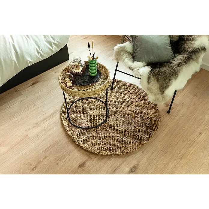 Esbeco RentierfellBraun/Weiß, 100 % Echtfell, 110 x 70 cm - Einrichtungsszene mit rundem Teppich aus Naturfaser, Beistelltisch mit Deko und Sessel mit Kissen und Fellimitat für gemütliches Ambiente.