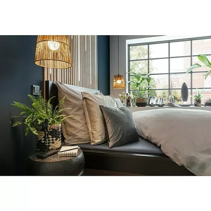 Manta para sofá Happy - 150 x 200 cm, Negro - Un dormitorio moderno con pared azul oscuro, cabecero de madera y cama con almohadas claras. Lámparas colgantes tejidas y plantas verdes añaden calidez.