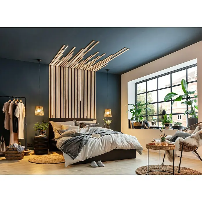 Juteteppich Nature 502 - Naturbraun, Durchmesser: 100 cm, 100 % Jute - Schlafzimmer mit einem modernen Bett, Holzakzenten und Pflanzen. Das Bett ist mit Kissen und einer Decke dekoriert, was eine gemütliche Atmosphäre schafft.