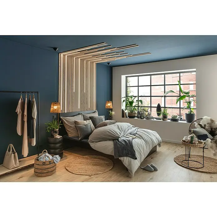 Juteteppich Nature 502 - Naturbraun, Durchmesser: 100 cm, 100 % Jute - Schlafzimmer mit dunklen Akzenten und Holzelementen. Das Bett ist mit grauer Bettwäsche bezogen, ergänzt durch dekorative Kissen und einen warmen Teppich.