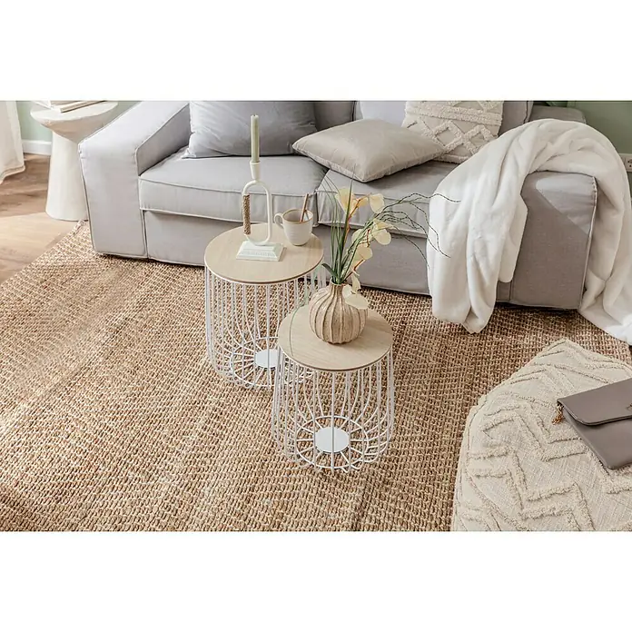 Decke HappyElfenbein, 200 x 150 cm, 100 % Polyester - Zwei runde Beistelltische mit Drahtgestell und Holzplatte stehen auf einem Teppich neben einem grauen Sofa. Dekorative Gegenstände schmücken die Tische.