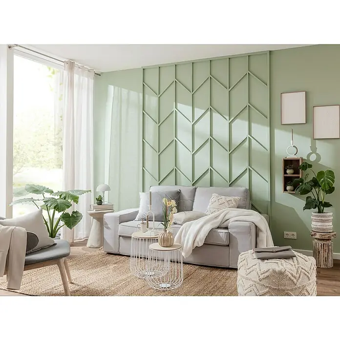 Alpina Wandfarbe Feine FarbenHüterin der Freiheit, Matt, 2,5 l, Konservierungsmittelfrei - Wohnzimmer mit einem grauen Sofa, dekorativen Kissen und einer hellgrünen Wand mit geometrischem Muster.
