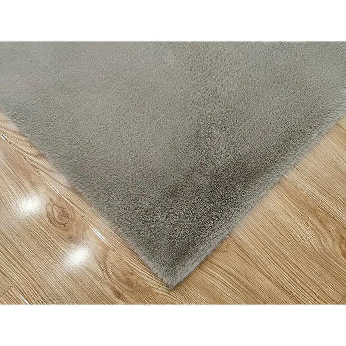 Alfombra de pelo corto Bunny - Taupé, 110 x 60 cm, 100% poliéster - Primer plano de una alfombra gris y esponjosa colocada sobre un suelo de madera, creando un ambiente cálido.