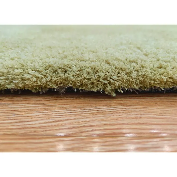 Alfombra de pelo corto Hong Kong - Aceite, 115 x 60 cm, Poliéster - Primer plano de una alfombra shaggy beige sobre un suelo de madera, mostrando su suave textura y tacto lujoso.