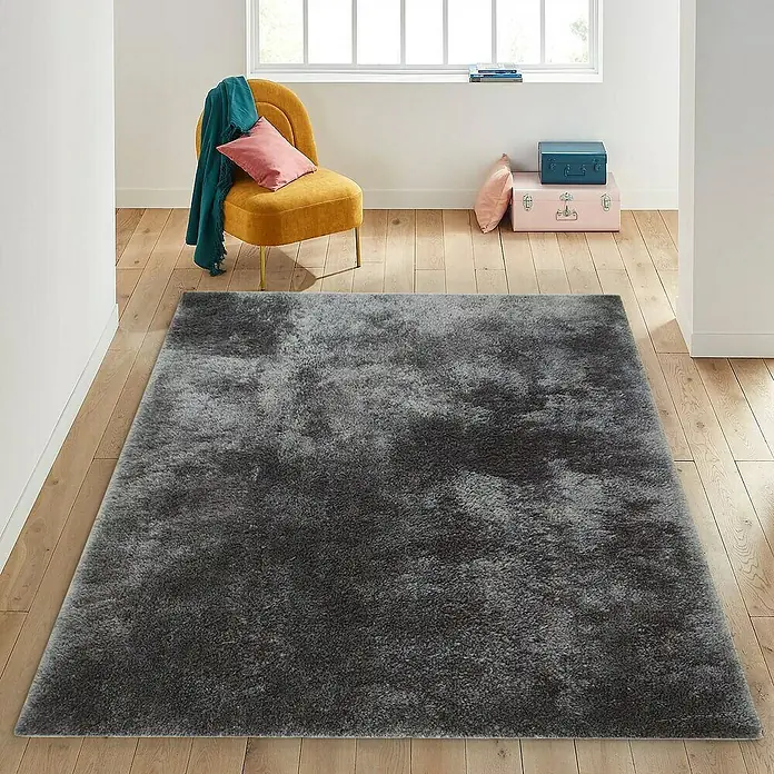 Alfombra de pelo largo Bolonia - Café, 115 x 60 cm, 100% Poliéster - Una alfombra gris y mullida se coloca en una habitación luminosa con suelos de madera, dando un toque acogedor a la decoración interior.