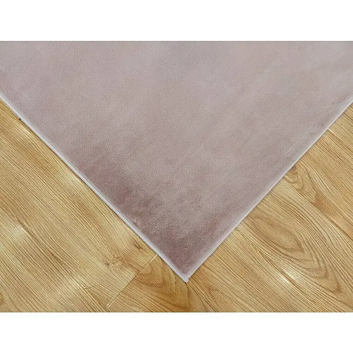 Alfombra de pelo corto Aiden - Rosa, 230 x 160 cm, Poliéster - Primer plano de una alfombra rosa suave colocada sobre un piso de madera clara, mostrando su textura y paleta de colores suaves.
