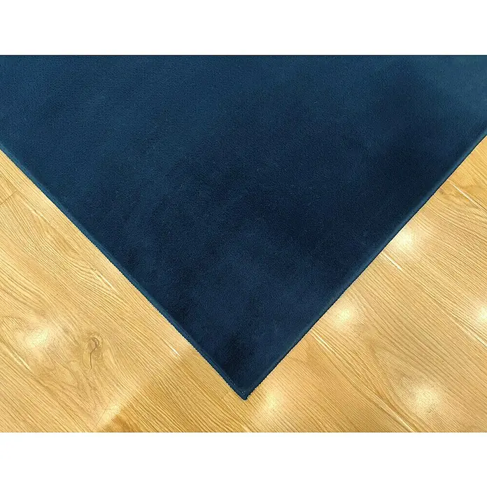 Alfombra de pelo corto Aiden - Azul, 170 x 120 cm, Poliéster - Primer plano de una alfombra azul oscuro sobre un piso de madera clara, destacando la textura y el color de la alfombra.