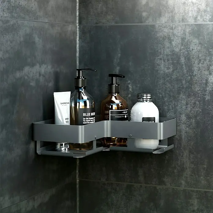 Cesta de baño angular Balance - 11 x 24 x 6 cm, Metal, Gun grey - Estante de esquina con diversos productos de cuidado como loción de lavado, champú y gel de ducha en una pared de baño gris.