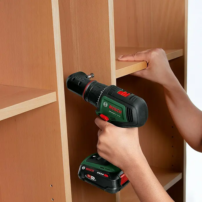 Bosch Power for All 18V Akku-Bohrschrauber AdvancedDrill 18V-80 QuickSnap - 18 V, Ohne Akku, 78 Nm, 3 Aufsätze - Ein Bosch Akku-Bohrschrauber wird verwendet, um ein Regal in einem Schrank zu befestigen. Das Gerät ist grün und schwarz.