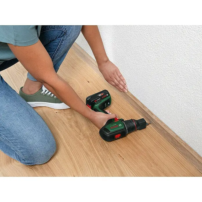 Bosch Power for All 18V Akku-Bohrschrauber AdvancedDrill 18V-80 QuickSnap - 18 V, Ohne Akku, 78 Nm, 3 Aufsätze - Ein Akku-Bohrschrauber der Marke Bosch wird verwendet, um eine Sockelleiste an einer Wand zu befestigen. Präzise und kabellos montieren mit Bosch.