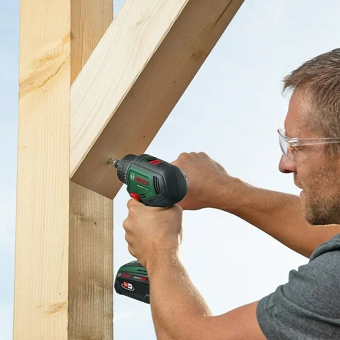Bosch Power for All 18V Akku-Bohrschrauber AdvancedDrill 18V-80 QuickSnap - 18 V, Ohne Akku, 78 Nm, 3 Aufsätze - Ein Handwerker benutzt einen Bosch Akkuschrauber, um Holz zu befestigen, wobei er eine Schutzbrille trägt, um die Augen zu schützen.