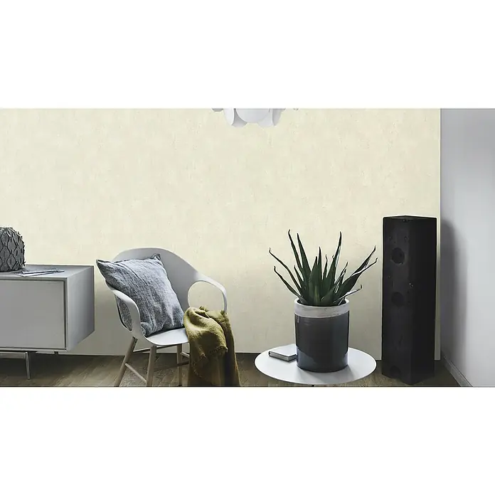 Rasch Vliestapete - Beige, Uni, 10,05 x 0,53 m, Spachtelstruktur - Eine gemütliche Ecke mit einer cremefarbenen Mustertapete, einem Stuhl mit Kissen, einer Pflanze und einem Lautsprecher. Die Tapete sorgt für Flair.