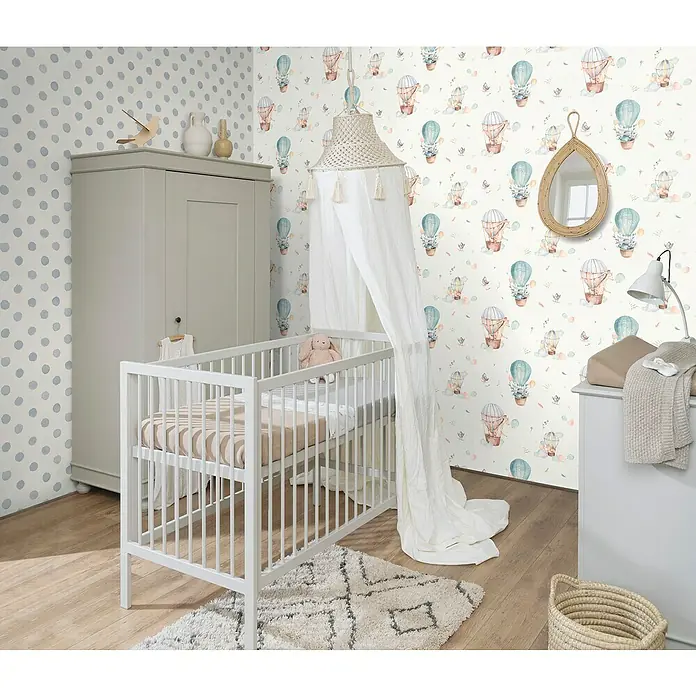 Rasch Bambino XIX Vliestapete Punkte - Blau, Grafisch, 10,05 x 0,53 m - Ein Kinderzimmer mit einem weißen Kinderbett, einem grauen Schrank und einer Wickelkommode, dekoriert mit Luftballon-Tapete und einem Baldachin.