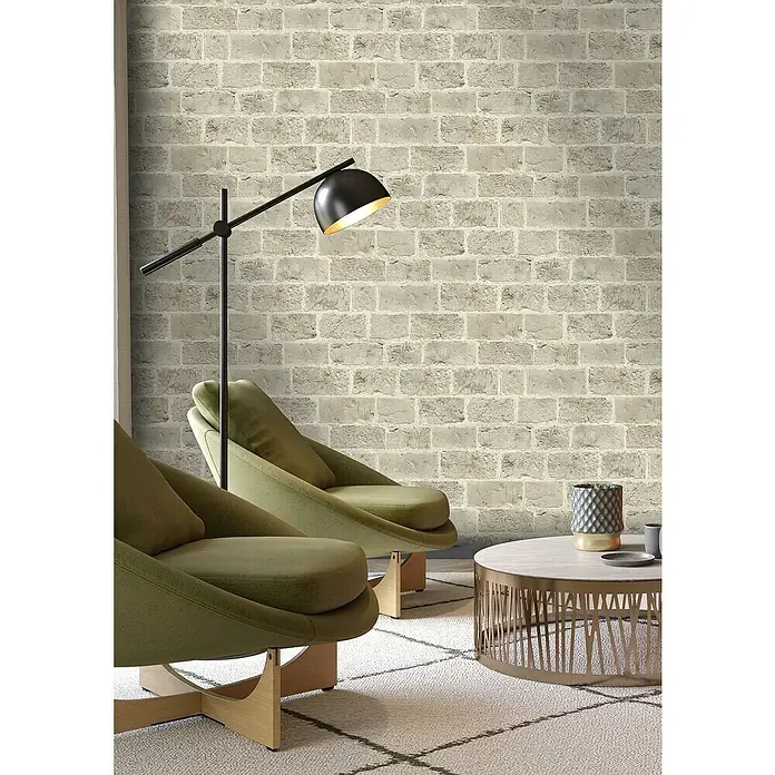 Rasch Symphony Vliestapete Backstein - Dunkelbeige, Steinoptik, 10,05 x 0,53 m - Einrichtungsidee mit zwei grünen Sesseln, einem Beistelltisch und einer Stehlampe vor einer grauen Backsteinmauer.
