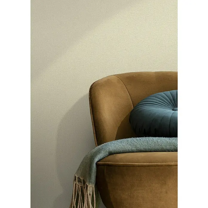 Rasch Tapetenwechsel Vliestapete Classic Style - Braun/Grau, Uni, 10,05 x 0,53 m - Nahaufnahme eines braunen Sessels mit blauem Kissen und grauer Decke vor einer getexturierten Wand.