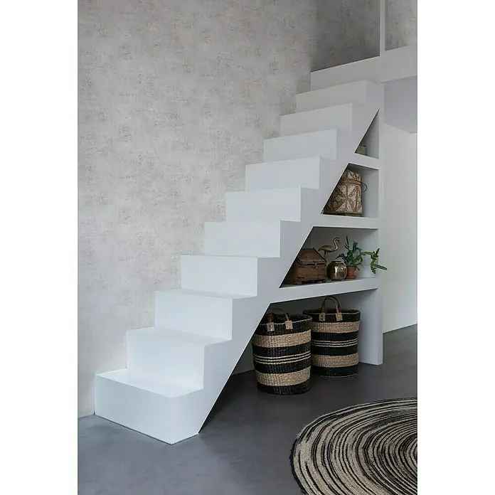Rasch Vliestapete Beton - Altweiß, Betonoptik, 10,05 x 0,53 m - Weisse Treppe mit integrierten Regalen, geschmückt mit Körben, Pflanzen und Dekoration, die einen stilvollen und funktionalen Raum schafft.