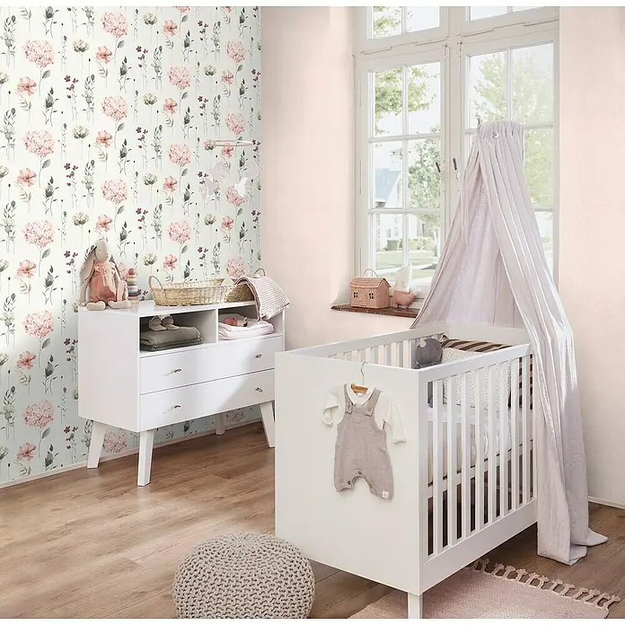 Rasch Bambino XIX Vliestapete - Beige, Uni, 10,05 x 0,53 m - Das helle Kinderzimmer mit einem weißen Kinderbett, einer Kommode und einer floralen Tapete wirkt freundlich und einladend.