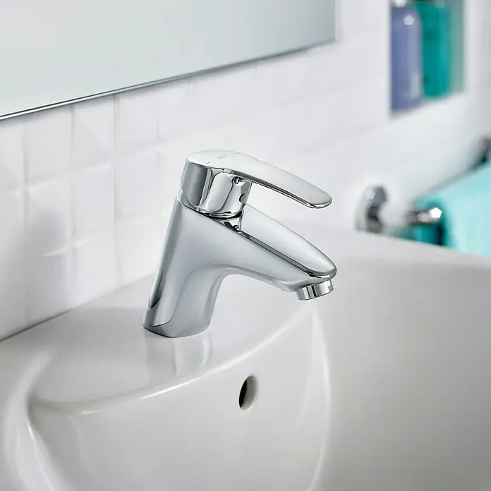 Roca Eos-N Grifo de lavabo - Cromo, Brillante - Primer plano de un moderno grifo cromado sobre un lavabo blanco, mostrando un diseño elegante y minimalista.