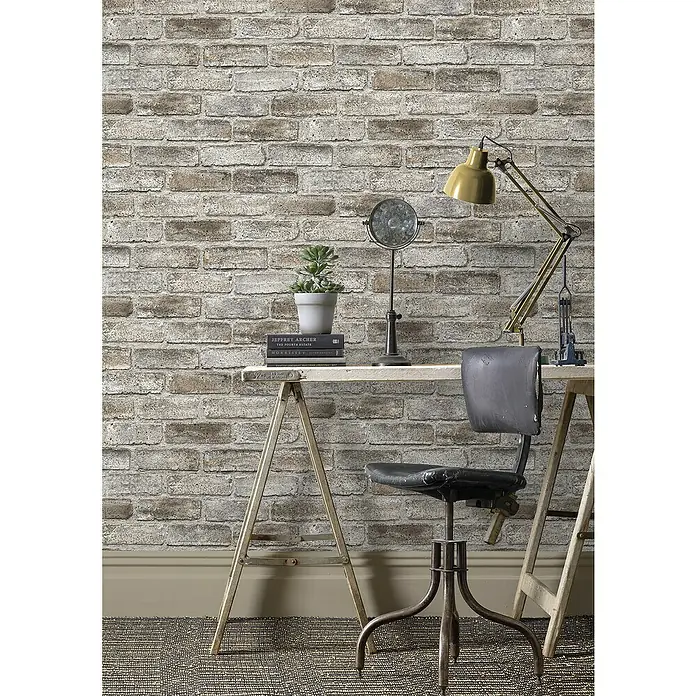 Rasch Symphony Vliestapete Stein - Steingrau, Steinoptik, 10,05 x 0,53 m - Arbeitszimmer mit Schreibtisch, Stuhl und Lampe vor einer Backsteinwand. Schafft eine gemütliche und dennoch professionelle Atmosphäre.