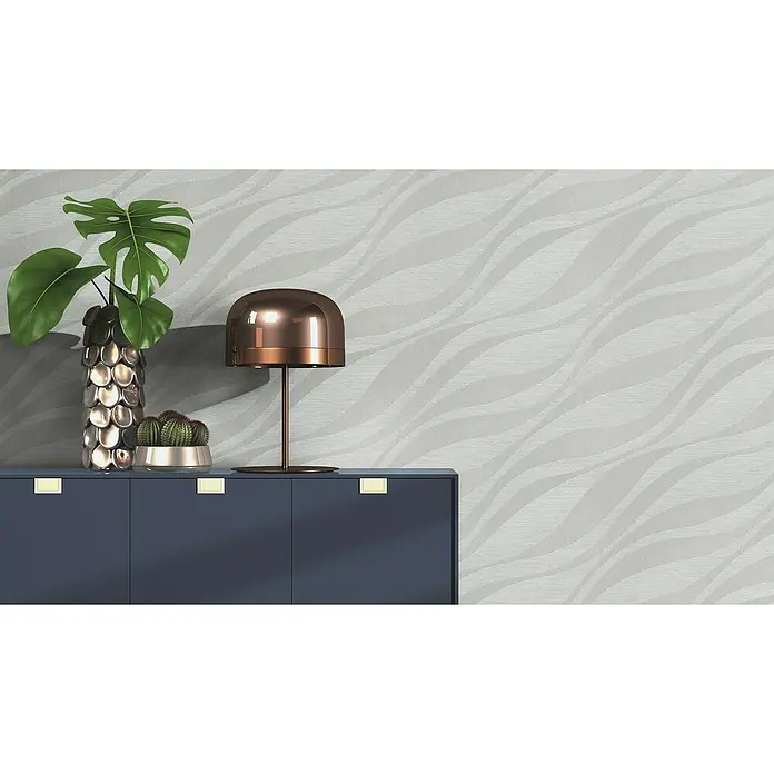 Rasch Sky Lounge Vliestapete Wellen - Silbergrau, Wellen, 10,05 x 0,53 m - Elegante Kommode in dunklem Marineblau mit dekorativer Lampe, Vase und Kaktus, die eine stilvolle und moderne Wohnraumgestaltung unterstreichen.