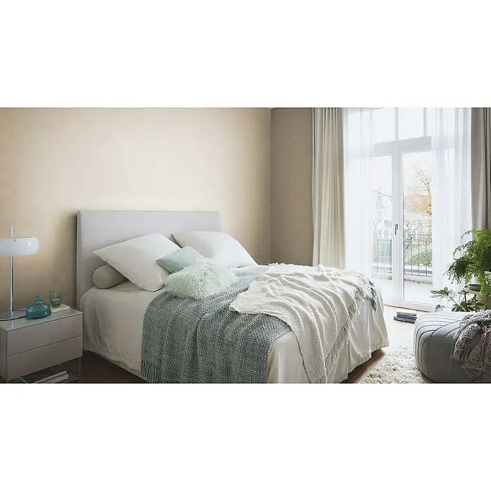 Rasch African Queen III Vliestapete Felloptik - Hellbraun, Uni, 10,05 x 0,53 m - Ein gemütliches Schlafzimmer mit einem weichen Bett, hellen Kissen und einer Tagesdecke lädt zum Entspannen ein. Der Nachttisch ist modern gestaltet.