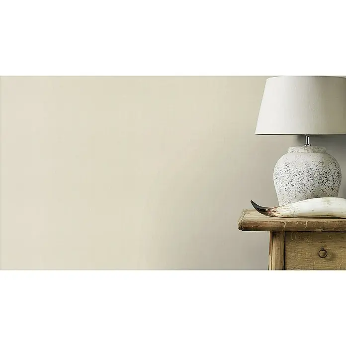 Rasch Country Charme Vliestapete Leinen-Uni - Creme hell, Uni, 10,05 x 0,53 m - Dekorative Tischleuchte mit einem Lampenschirm aus hellem Stoff auf einem rustikalen Holztisch, ergänzt durch ein stilvolles Dekoelement.