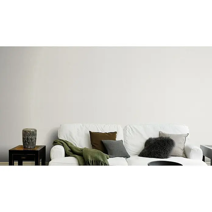 Rasch Color your life Vliestapete Struktur-Uni - Hellgrau, Uni, 10,05 x 0,53 m - Nahaufnahme eines stilvollen Sofas mit Kissen und Decke in einem minimalistischen Wohnzimmer. Ein dekoratives Element steht auf dem Tisch.