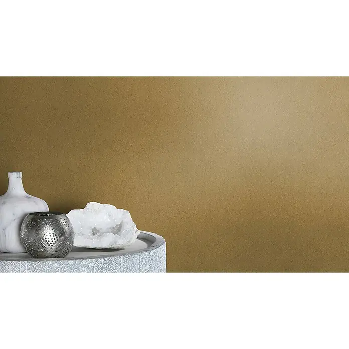 Rasch African Queen III Vliestapete Felloptik - Gold, Uni, 10,05 x 0,53 m - Dekorative Tischszene mit einer Marmorvase, einem silbernen Kerzenhalter und einem Quarzstück auf einer kunstvoll verzierten Oberfläche.