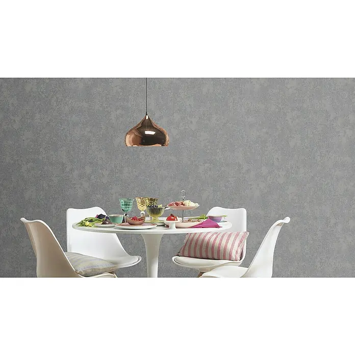 Rasch Color your life Vliestapete Struktur-Uni - Dunkelgrau, Steinoptik, 10,05 x 0,53 m - Eine Nahaufnahme eines Esszimmers mit einem weißen Tisch und Stühlen, einem goldenen Lampenschirm und einem grauen Hintergrund.