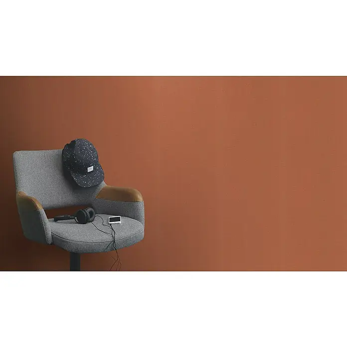 Rasch Wall Textures VI Vliestapete Leinen-Uni - Terra, Uni, 10,05 x 0,53 m - Ein grauer Drehstuhl mit braunen Armlehnen, Kopfhörern, einer Mütze und einem MP3-Player vor einem einfarbigen Hintergrund.