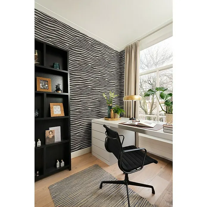 Rasch African Queen III Vliestapete Zebrafell - Schwarz-Weiß, Tieroptik, 10,05 x 0,53 m - Eine Nahaufnahme eines modernen Büroraums mit einem schwarzen Bürostuhl vor einem weißen Schreibtisch, ergänzt durch ein markantes Zebra-Tapetenmuster.