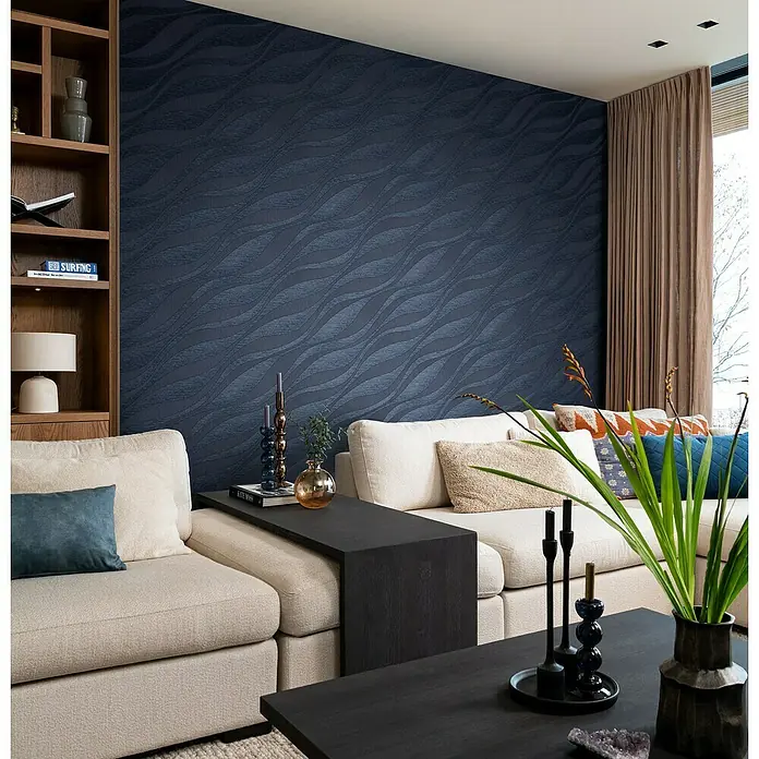 Rasch Sky Lounge Vliestapete Wellen - Nachtblau, Wellen, 10,05 x 0,53 m - Elegantes Wohnzimmer mit einem stilvollen Sofa, dunklen Akzenttischen und einer auffälligen, blauen Wandtapete mit Wellenmuster.