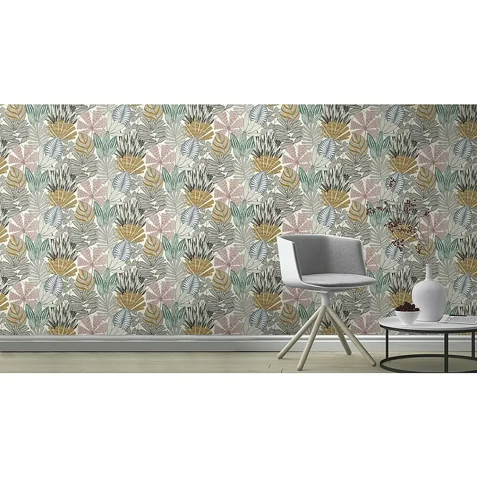 Rasch Symphony Vliestapete Nature - Bunt, Floral, 10,05 x 0,53 m - Eine Nahaufnahme einer Wand mit einer bunten Blättertapete, einem Stuhl und einem Beistelltisch mit Dekorationen.