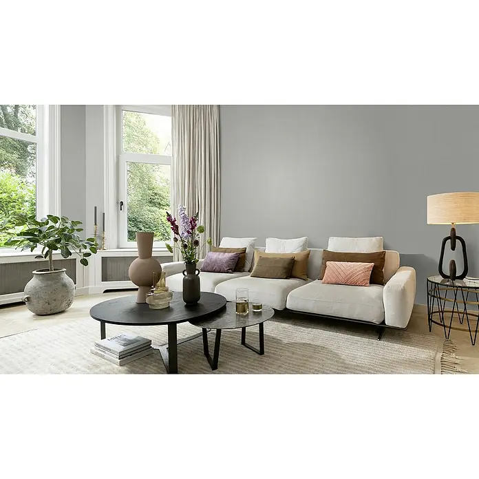 Rasch Color your life Vliestapete Struktur-Uni - Silbergrau, Uni, 10,05 x 0,53 m - Elegantes Wohnzimmer mit einem modularen Sofa in Weiß, akzentuiert durch farbige Kissen. Ein Couchtisch-Set und eine Stehlampe runden das Ambiente ab.