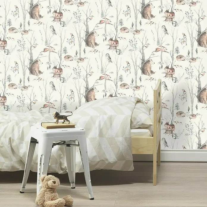 Rasch Kids World Vliestapete Tiere - Hellbraun, Tieroptik, 10,05 x 0,53 m - Kinderzimmer mit einem Bett und einem weißen Hocker mit einem Teddybär und einem Löwen darauf, vor einer Tapete mit Tiermotiven.