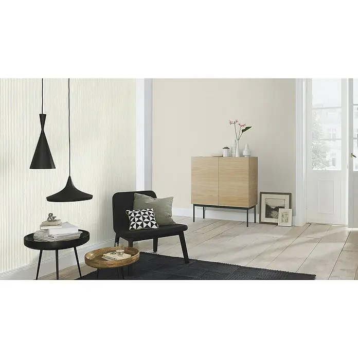 Rasch Wall Textures VI Vliestapete Uni - Offwhite, Uni, 10,05 x 0,53 m - Ein stilvolles Wohnzimmer mit zwei schwarzen Hängelampen, einem schwarzen Sessel und einem hellen Holzschrank, der eine gemütliche Atmosphäre schafft.