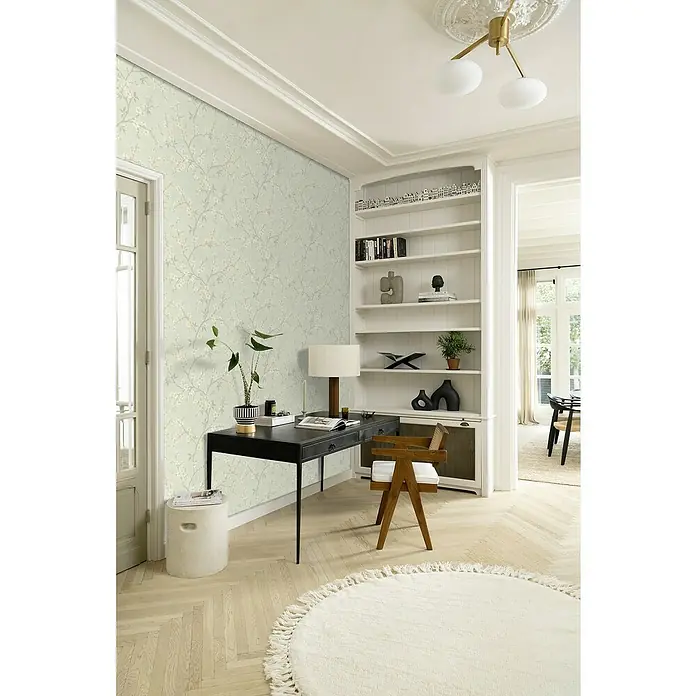 Rasch Country Charme Vliestapete Kirschblüten - Pastellblau, Floral, 10,05 x 0,53 m - Das Bild zeigt ein stilvolles Arbeitszimmer mit einem dunklen Schreibtisch und einem hellen, runden Teppich auf einem hellen Holzboden. Elegante und helle Wandtapete.