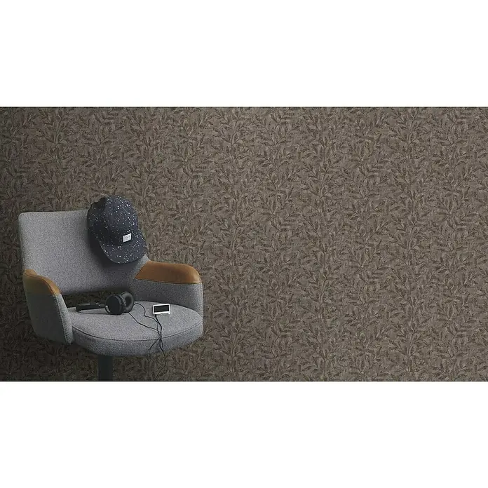 Rasch Factory V Vliestapete Blätter - Dunkelbraun, Floral, 10,05 x 0,53 m - Ein grauer Drehstuhl mit braunen Akzenten, darauf eine Mütze, Kopfhörer und ein Musikplayer vor einem Blattmuster-Hintergrund.