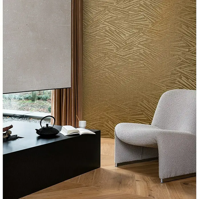Rasch Sky Lounge Vliestapete Mikado - Gold, Grafisch, 10,05 x 0,53 m - Nahaufnahme eines stilvollen Interieurs mit einem Bouclé-Sessel, einem schwarzen Tisch und einer Teekanne vor einer gemusterten Wand.